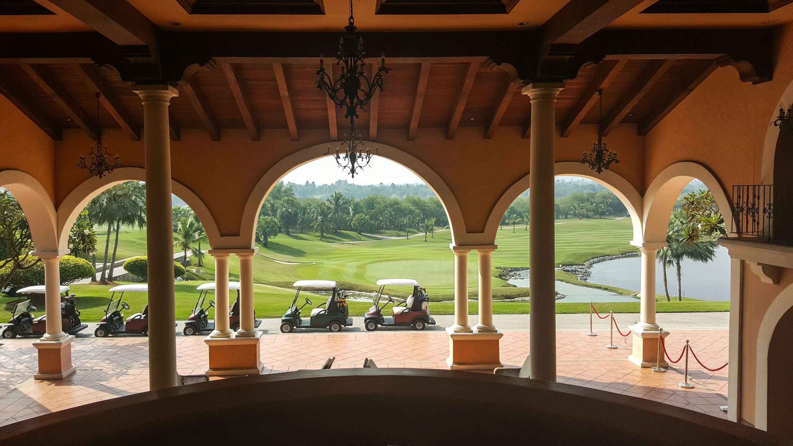 row of golf car stand by front of hotel near golf field