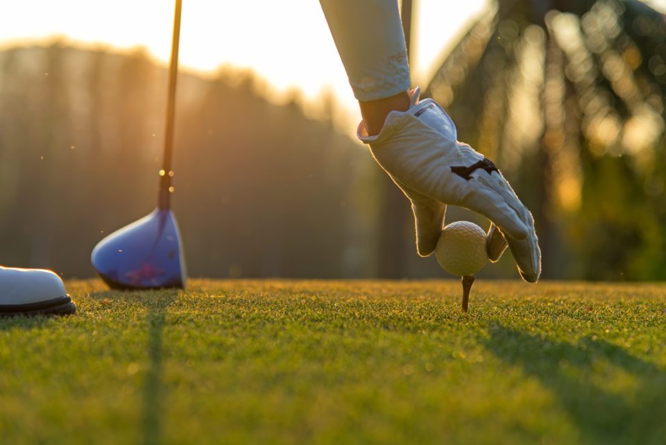 Woman putting golf ball on tee